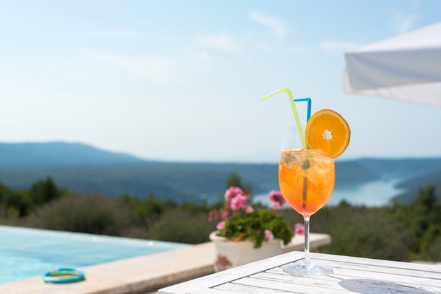 Aperol spritz sul tavolo a bordo piscina con vista sulla baia di Arsa