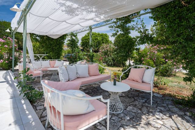 Pergola Ville Štefanije s ružičastim sofama u zelenilu